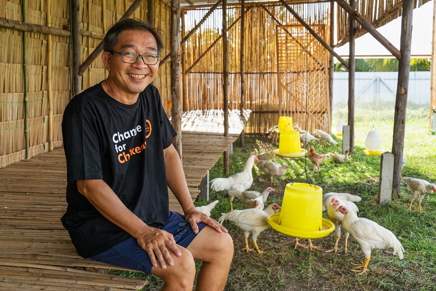 The owner of Kid Dee Farm in a spacious chicken coop